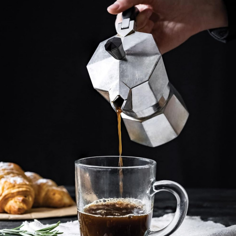 Una persona sirve café en una taza con una cafetera italiana